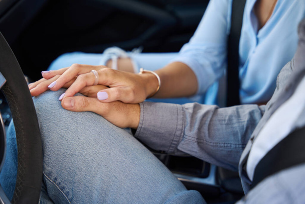 Részleges kép a férfiról és a nőről, amint egymás kezét fogják az autóban. A romantikus kapcsolat fogalma. Az utazás, utazás és nyaralás ötlete - Fotó, kép