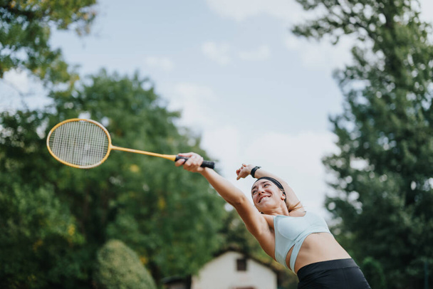 Kadın, badminton oyuncusu raketle mekiğe uzanıyor.. - Fotoğraf, Görsel