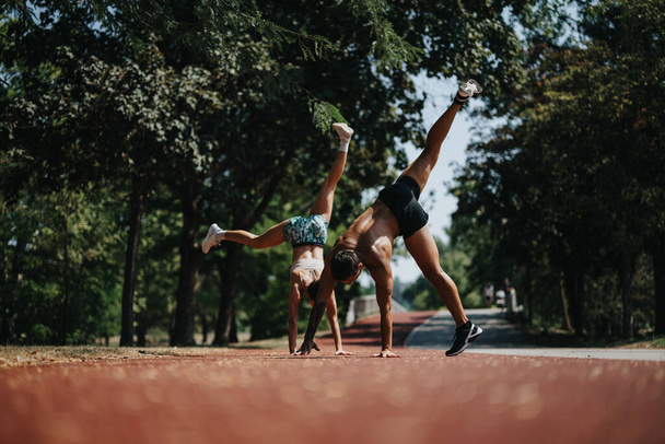 Gli atleti attivi praticano Cardio e Cartwheel nell'ambiente del parco naturale nella giornata soleggiata - Foto, immagini
