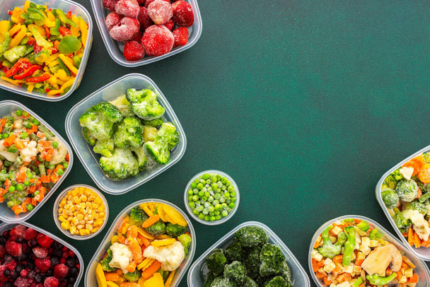 Preparación de alimentos para el invierno, congelación de verduras frescas en el verano en el refrigerador, varias verduras congeladas en platos de plástico sobre un fondo verde - Foto, Imagen