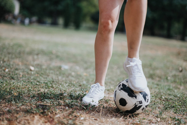 Un atleta atractivo entrena al aire libre, realizando trucos de fútbol y haciendo malabares con una pelota de fútbol. Chica con una pierna en un balón de fútbol. - Foto, imagen