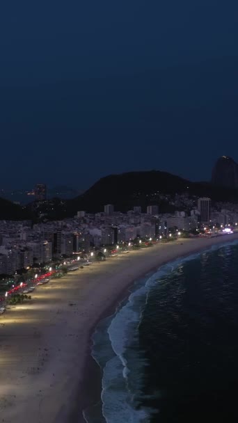 Рио-де-Жанейро ночью. Пляж Копакабана и Атлантический океан. Вечерние Сумерки. Голубой час. Вид с воздуха. Бразилия. Дрон летит вперед и вверх. Вертикальное видео - Кадры, видео