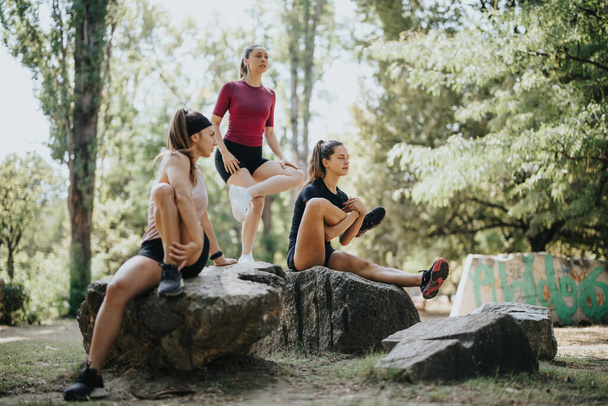 Fit and active women enjoying a sunny day in a city park, stretching and warming up together. Promoting a healthy lifestyle through outdoor sports activities. - Photo, Image