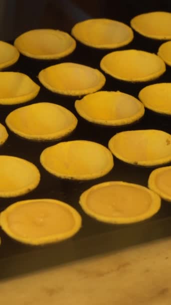 Pasticciere Versare la Crema Custard all'Uovo nelle Torte Pastello De Nata. Pasticceria tradizionale portoghese alla crema di uova. Crostate in una pasticceria. Video verticale - Filmati, video