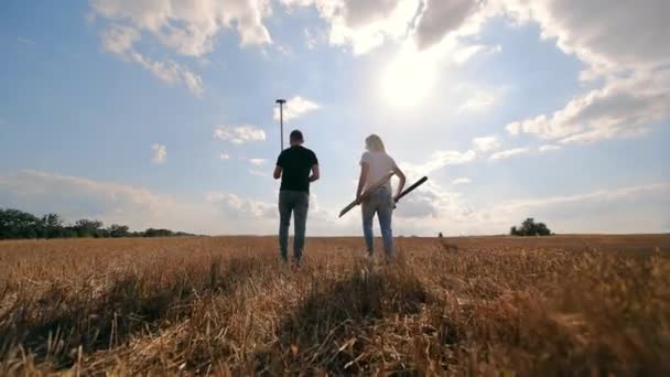 Agricultores caminando en el campo cosechado, hombre y mujer con herramientas agrícolas. Medición de los límites de campo - Metraje, vídeo