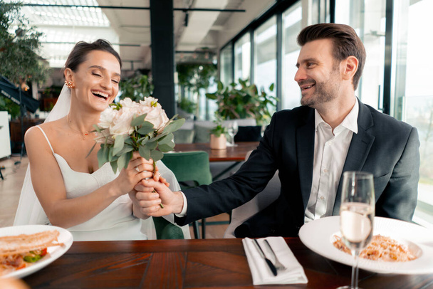 πορτρέτο του χαμογελαστού γαμπρού και της νύφης στην αγάπη νεόνυμφους γάμο στο εστιατόριο κατά τη διάρκεια του εορτασμού του έρωτα ρομαντισμού - Φωτογραφία, εικόνα