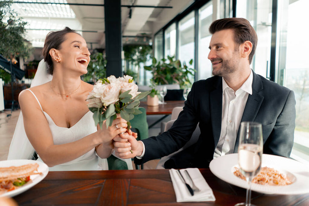 portret van een glimlachende bruid en bruidegom in liefde pasgetrouwden bruiloft in restaurant tijdens de viering van de liefde romantiek - Foto, afbeelding