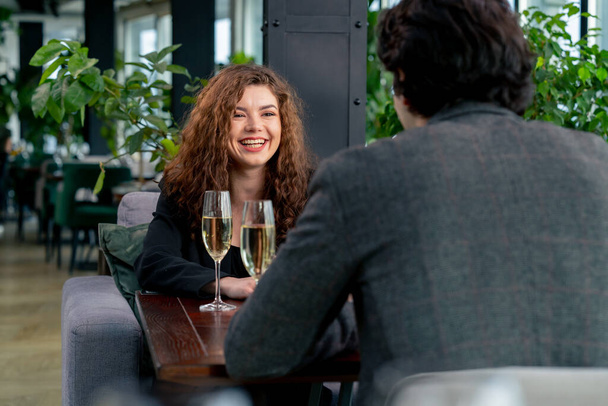 İş görüşmesinde gülümseyen kıvırcık bir kadının portresi mi yoksa şampanya kadehli bir adamla randevusu mu? - Fotoğraf, Görsel