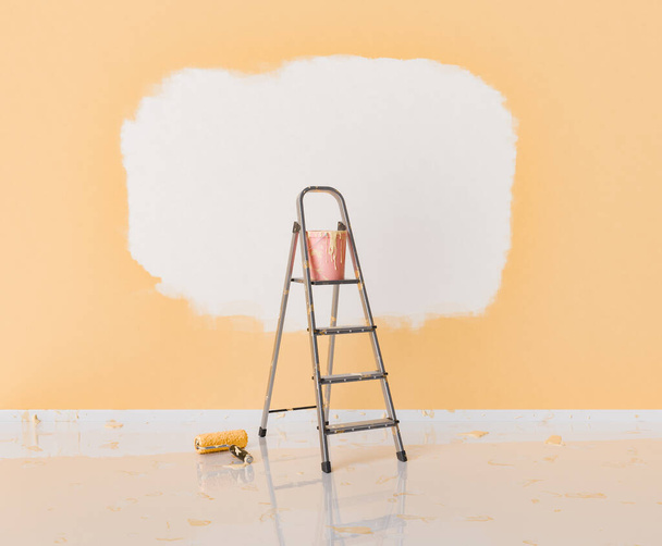 Renderização 3D de uma cena de melhoria de casa interior com uma parede parcialmente pintada com laranja sobre branco, uma escada passo, e um rolo de pintura com salpicos no chão. conceito de renovação de casa. - Foto, Imagem