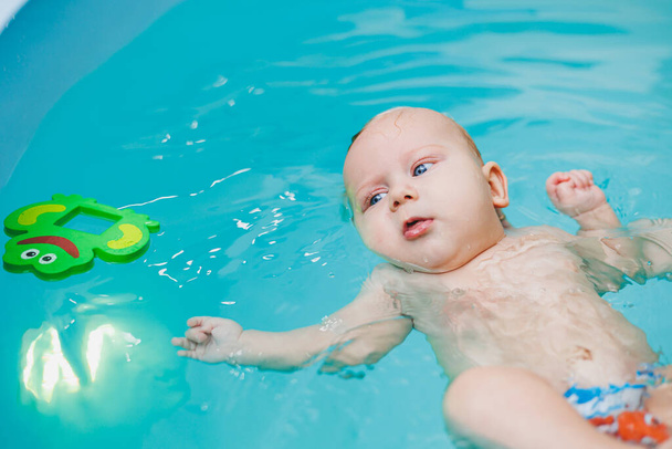 Kindern das Schwimmen beibringen. Ein Baby lernt mit einem Trainer in einem Pool schwimmen. Baby lernt schwimmen. Entwicklung von Kindern. - Foto, Bild