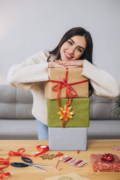 美しい幸せな女性は包み,自宅でクリスマスプレゼントを保持しています - 写真・画像