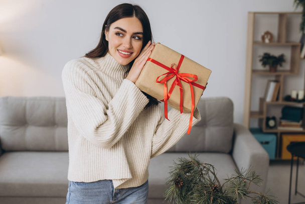 Güzel mutlu kadın evde Noel hediyelerini paketliyor ve tutuyor. - Fotoğraf, Görsel