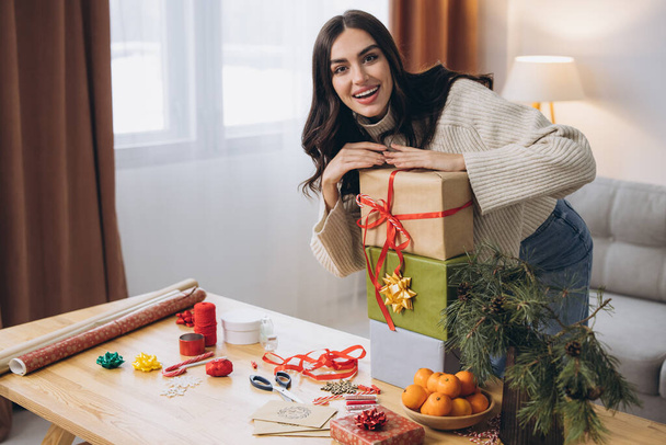 Bella donna felice sta avvolgendo e tenendo regali di Natale a casa - Foto, immagini