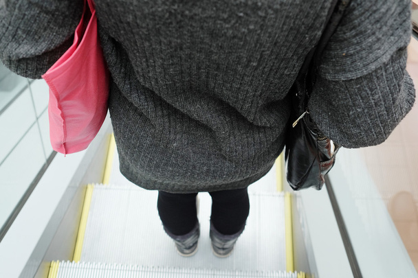 Woman using the escalator - Zdjęcie, obraz