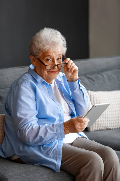 Femme âgée dans les lunettes en utilisant un ordinateur tablette à la maison - Photo, image