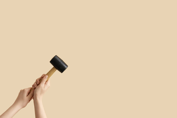 Mani femminili che tengono martello di gomma su sfondo beige - Foto, immagini