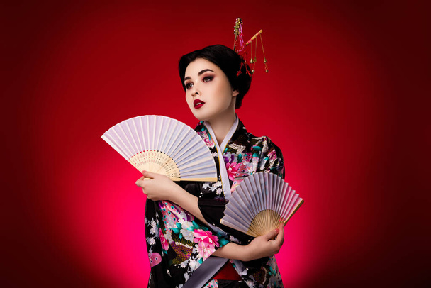 Foto de elegante señora vestido vestido japonés kimono buscando espacio vacío aislado sobre fondo de color rojo degradado. - Foto, imagen