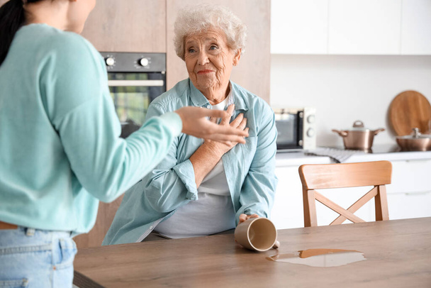 Femme âgée et sa fille contrariés par le thé renversé dans la cuisine - Photo, image
