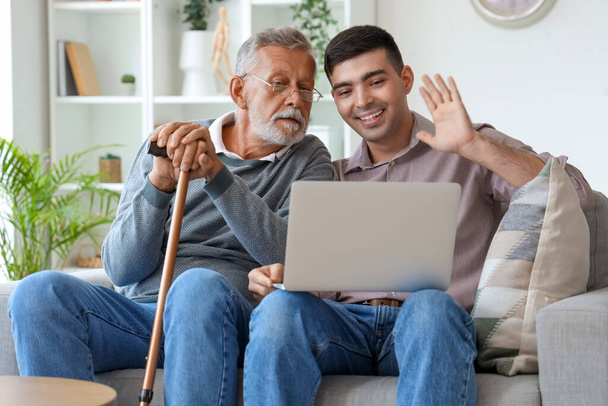 Senior man met zijn zoon video chatten thuis - Foto, afbeelding