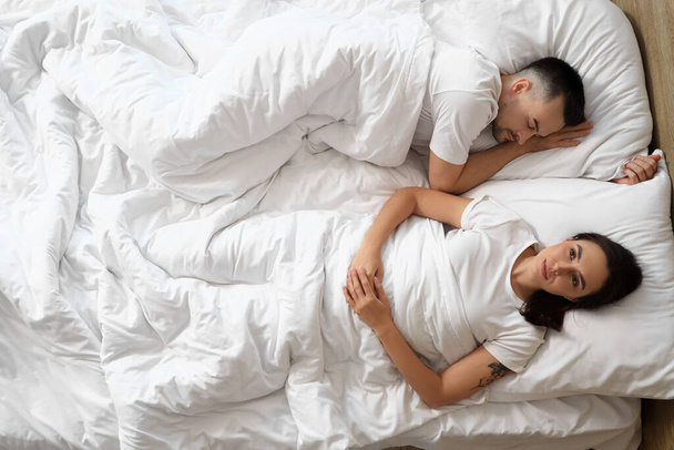 Ξύπνησε μια νεαρή γυναίκα με τον κοιμισμένο άντρα της στην κρεβατοκάμαρα, με θέα στην κορυφή - Φωτογραφία, εικόνα
