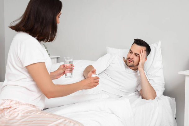 Молодий чоловік приймає таблетки від своєї дружини в спальні - Фото, зображення