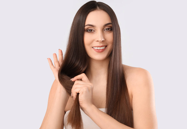 Young brunette woman with long hair on light background - Photo, Image