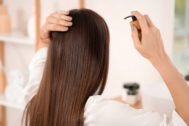 Mladá brunetka žena použití vlasový produkt v koupelně, pohled zezadu - Fotografie, Obrázek