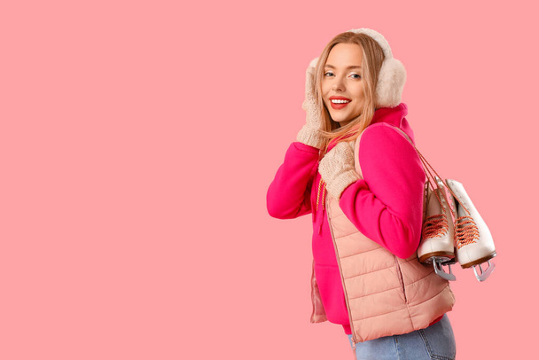 Happy young woman with ice skates on pink background - Photo, Image