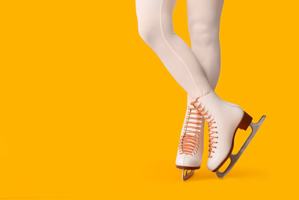 Πόδια από πατινέρ γυναικείας μορφής σε παγοπέδιλα σε κίτρινο φόντο - Φωτογραφία, εικόνα