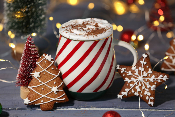 Copa de cacao caliente con galletas de jengibre y juguete de árbol de Navidad sobre una mesa de madera gris sobre fondo borroso - Foto, imagen