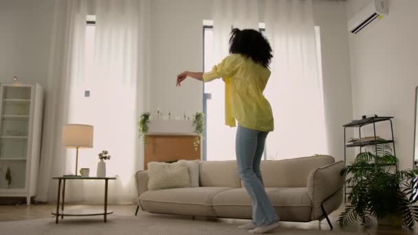 Lustige energische junge afroamerikanische ethnische Mädchen glücklich lächelnd Tänzerin tanzen zu Hause Wohnzimmer aktive Bewegung Tanz zur Musik Party-Wochenende genießen Umzug Mieter neue Wohnung - Filmmaterial, Video