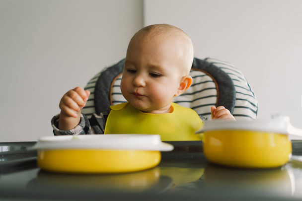 Sağlam beslenmiş küçük bir çocuk. Küçük kız parmak yemeği yiyor ve sebze tabağını karıştırıyor. Bebek sütten kesme BLW kendini besleme. - Fotoğraf, Görsel