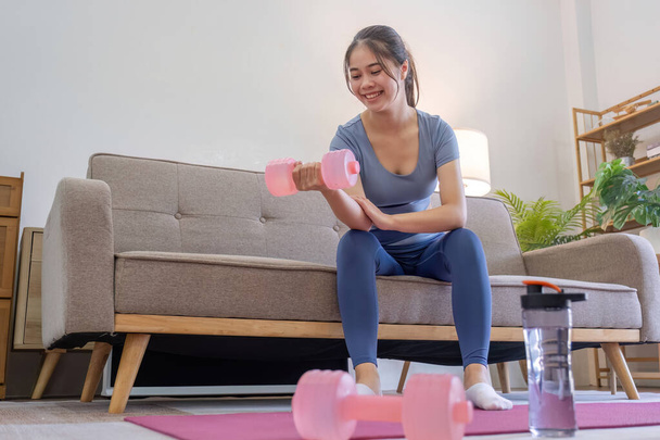 Fiatal ázsiai nő gyakorlat súlyzókkal otthon. - Fotó, kép