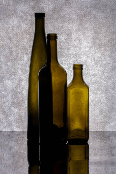 zátiší s barevnými skleněnými lahvemi na šedém pozadí - Fotografie, Obrázek