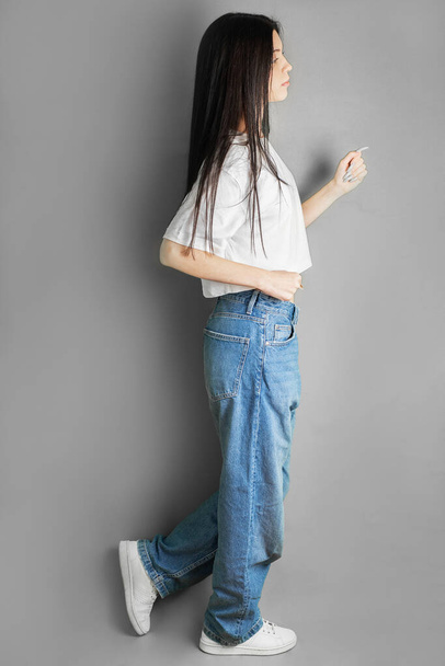 Full length portrait of a young teenager girl in a white T-shirt and jeans. - Photo, Image