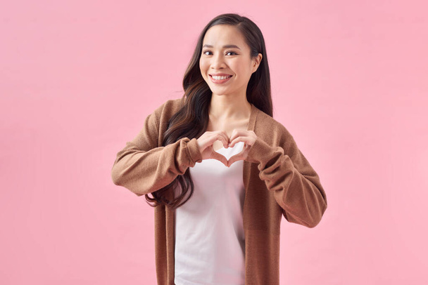 isolato ritratto di bella asiatico donna fare cuore simbolo da mani su rosa sfondo - Foto, immagini