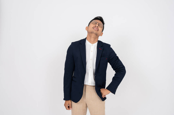 A stressed, failure Asian businessman stands on an isolated studio white background, showing a serious, unhappy, worried expression. - Photo, Image
