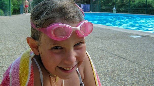 Chica joven saliendo de la piscina con sus gafas de buceo y toalla de baño en su - Foto, imagen