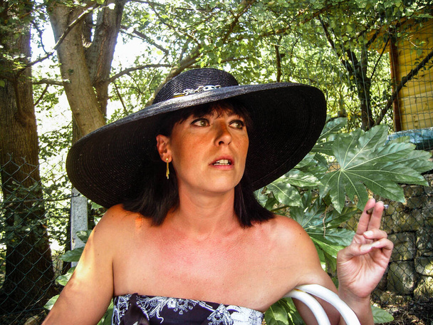 Femme avec un chapeau chapeau, de profil lors d'une garden party, cigare fumeur - Photo, image