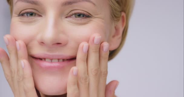 Vrouw aanraken gezicht, schoonheid en huid met glimlach, anti-aging cosmetische behandeling en schone huidverzorging. Natuurlijke cosmetica, gelukkig vrouwelijk model en gezicht met portret, dermatologie en wellness met glans. - Video