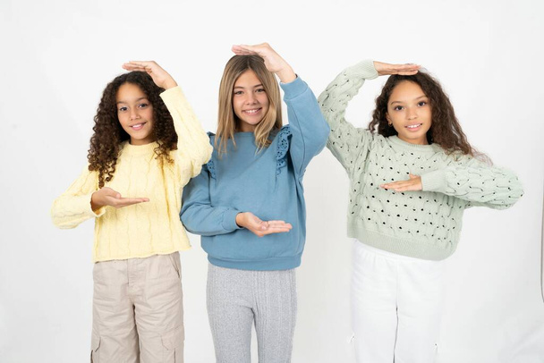3人の若い美しい多人種の少女が大きな看板を示す手でジェスチャーし,シンボルを測定します. カメラを見ている笑顔. - 写真・画像