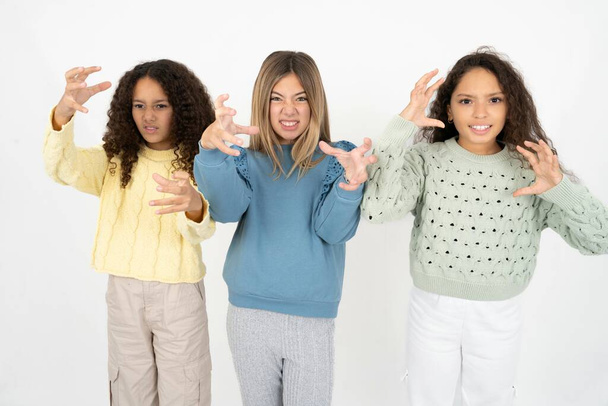 Drei junge schöne multirassische Mädchen schreien frustriert vor Wut, Hände versuchen zu würgen, schreien verrückt. - Foto, Bild