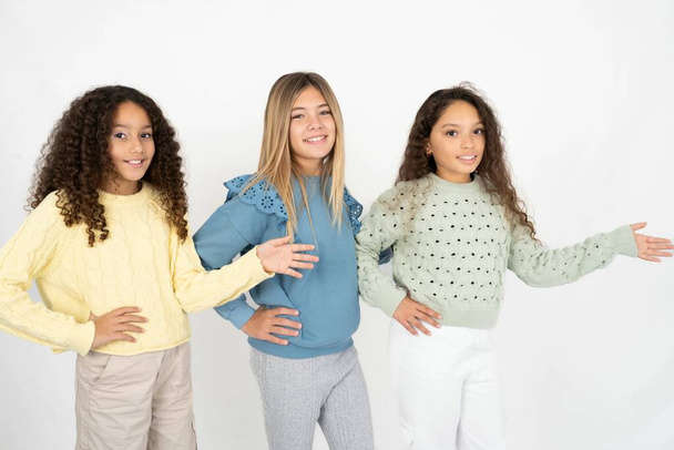 Trois jeunes filles multiraciales jeunes se sentent heureuses et gaies, souriantes et accueillantes, vous invitant à entrer avec un geste amical - Photo, image