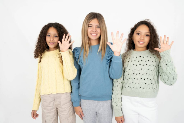 Kolme nuorta kaunista monirotuista tyttöä ilmestyy ja osoittaa sormilla numero viisi hymyillen itsevarmoina ja onnellisina.. - Valokuva, kuva