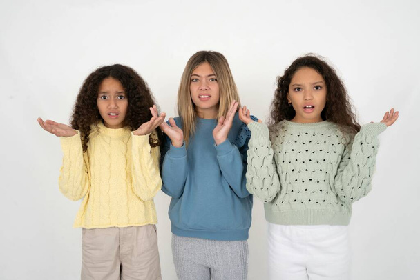 Indignant Three young beautiful multiracial kid girls gestures in bewilderment, frowns face with dissatisfaction. - Photo, Image