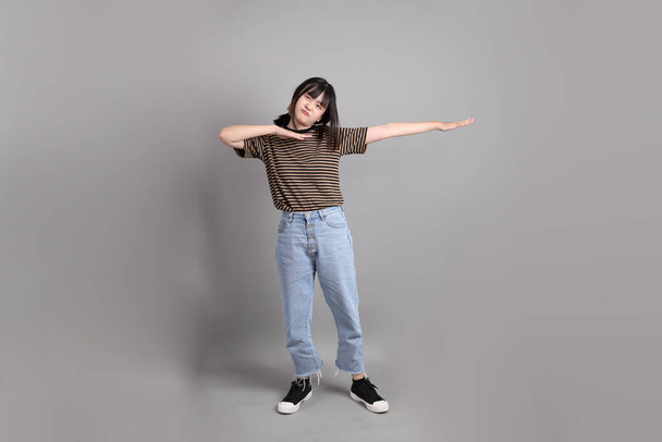 The full length of young adult Asian woman standing on the grey background. - Photo, Image