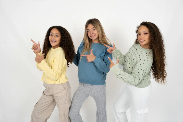 Trzy młode, piękne, wielorasowe dziewczynki wskazują na copyspace polecają zniżki sprzedażowe - Zdjęcie, obraz