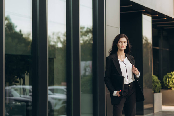 деловая женщина в костюме, стоящая рядом с офисным зданием - Фото, изображение