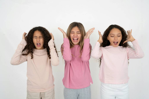 Three young beautiful multiracial kid girls goes crazy as head goes around feels stressed because of horrible situation - Photo, Image