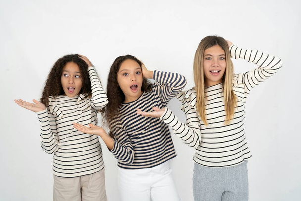 Sorprendido sorprendido sorprendido Tres chicas jóvenes y hermosas niños multirraciales toman de la mano ofreciendo proposición - Foto, imagen